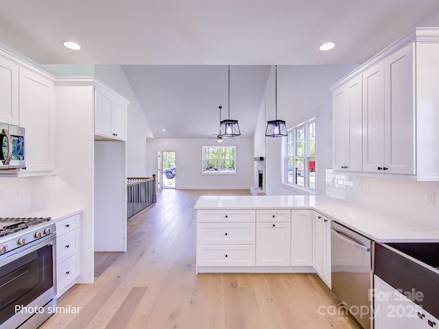 kitchen with white cabinets, backsplash, appliances with stainless steel finishes, and vaulted ceiling