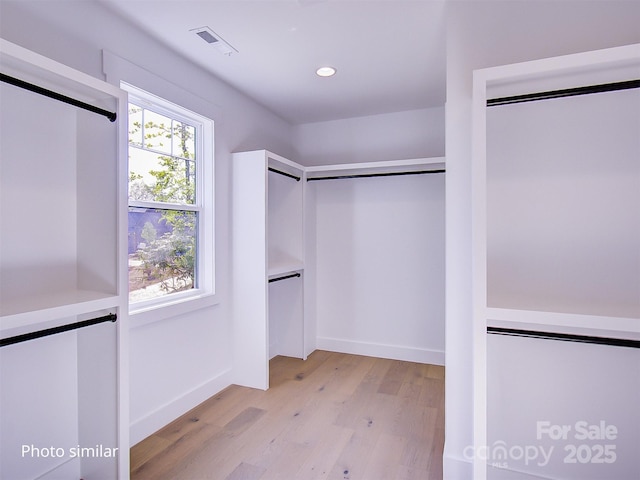 walk in closet with light hardwood / wood-style flooring