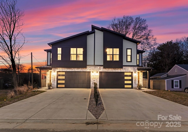 view of front facade with a garage, stone siding, and concrete driveway