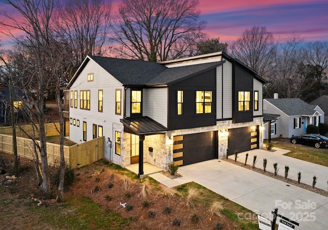 view of front of house featuring concrete driveway, an attached garage, fence, and stone siding