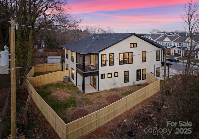 back house at dusk featuring a garage and central AC unit