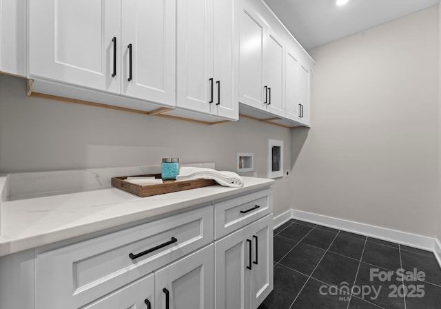 washroom with cabinets, dark tile patterned flooring, and hookup for a washing machine