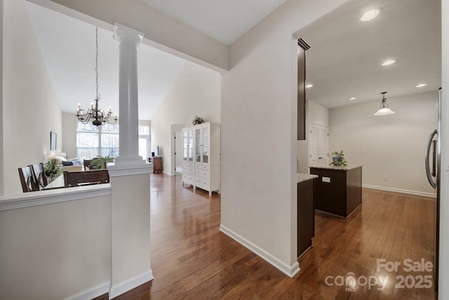 hall with decorative columns, a chandelier, and dark hardwood / wood-style floors