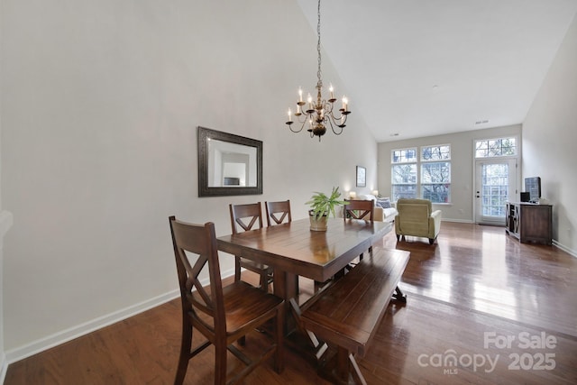 dining room with wood-type flooring, high vaulted ceiling, and a chandelier