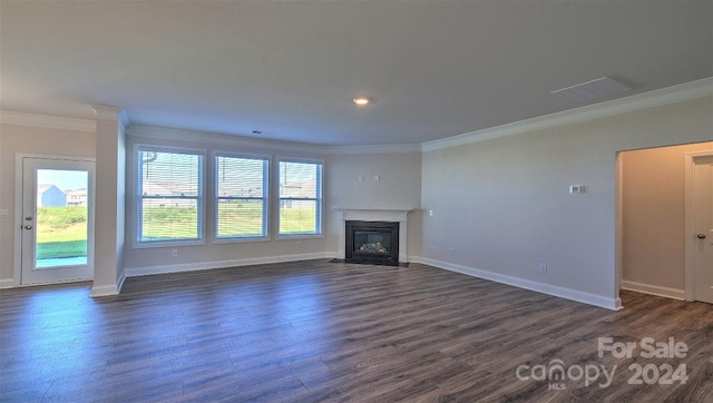 unfurnished living room with dark wood-type flooring, a healthy amount of sunlight, and ornamental molding