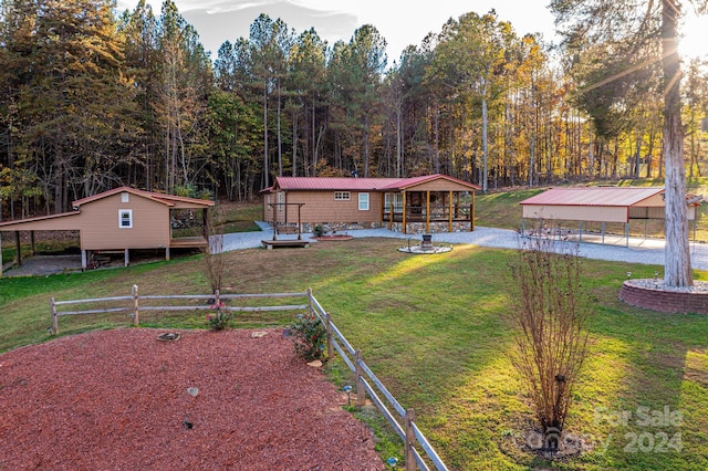 rear view of property featuring a lawn, a carport, and an outbuilding