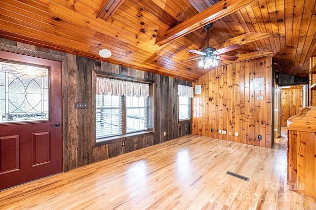 foyer entrance with lofted ceiling with beams, wood walls, and a healthy amount of sunlight