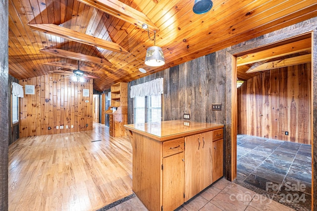 kitchen with wood ceiling, ceiling fan, wooden walls, lofted ceiling with beams, and light hardwood / wood-style floors