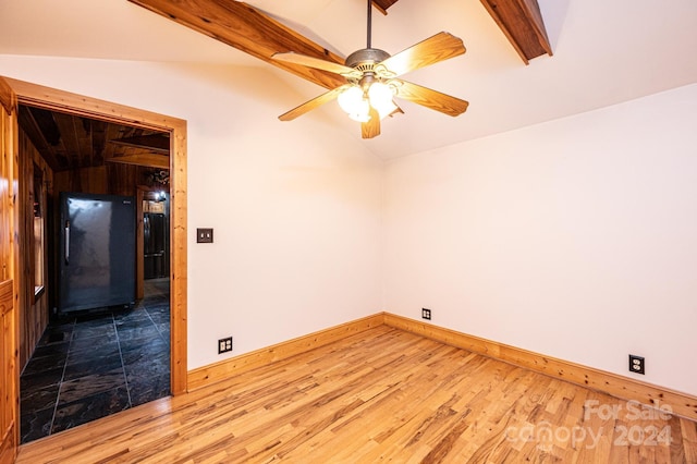 empty room with hardwood / wood-style floors, lofted ceiling with beams, and ceiling fan