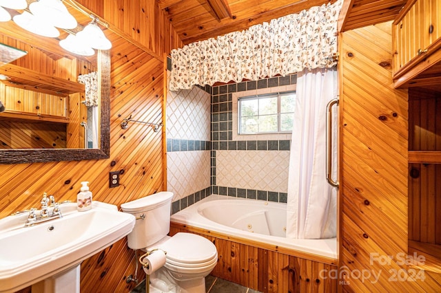 bathroom featuring a washtub, toilet, sink, and wooden walls