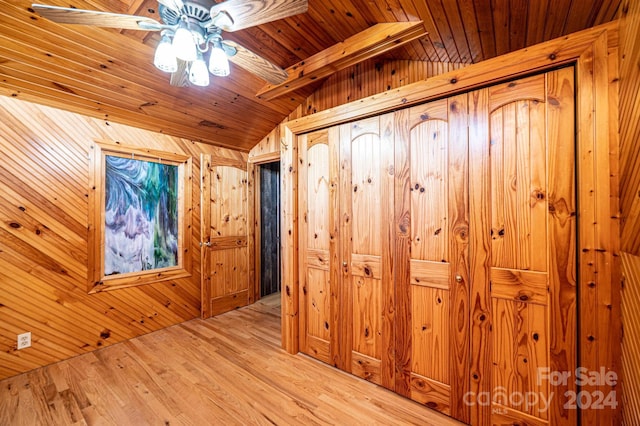 hall with lofted ceiling with beams, wood walls, wooden ceiling, and light hardwood / wood-style flooring