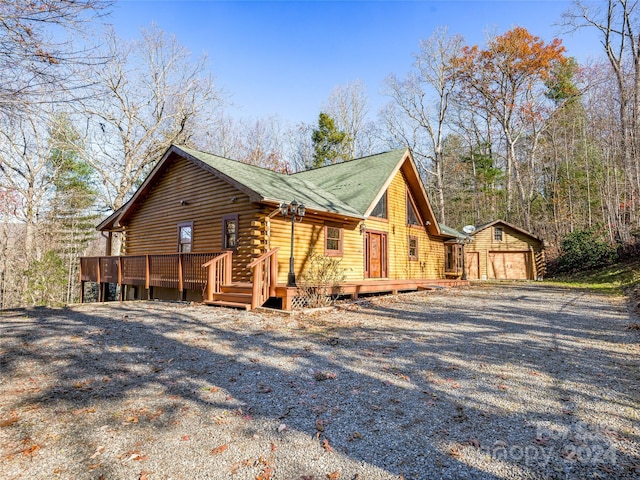 view of side of property featuring a wooden deck, an outbuilding, and a garage