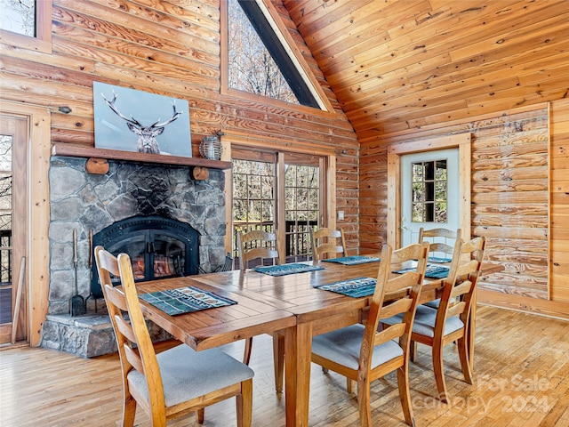 dining area with a fireplace, high vaulted ceiling, a healthy amount of sunlight, and light hardwood / wood-style floors