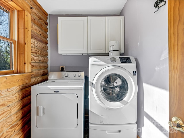 clothes washing area featuring cabinets and washing machine and clothes dryer