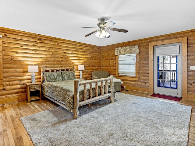 bedroom with log walls, access to outside, hardwood / wood-style flooring, and ceiling fan