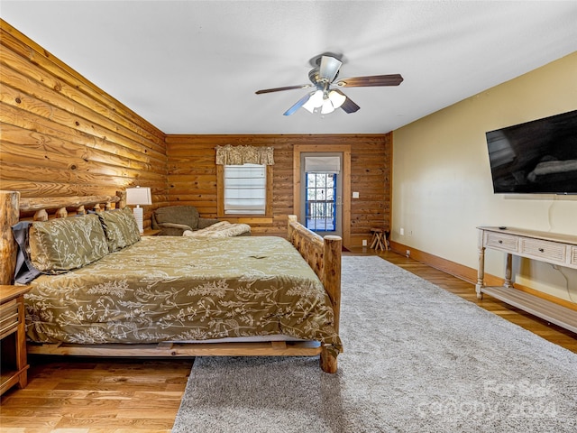 bedroom with ceiling fan, log walls, and hardwood / wood-style flooring