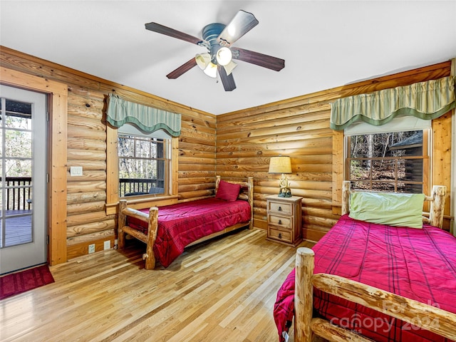 bedroom featuring access to exterior, wood-type flooring, rustic walls, and ceiling fan