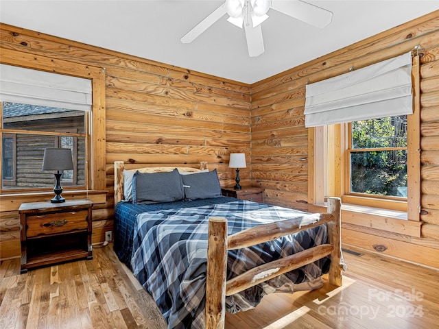 bedroom with wood-type flooring, rustic walls, and ceiling fan