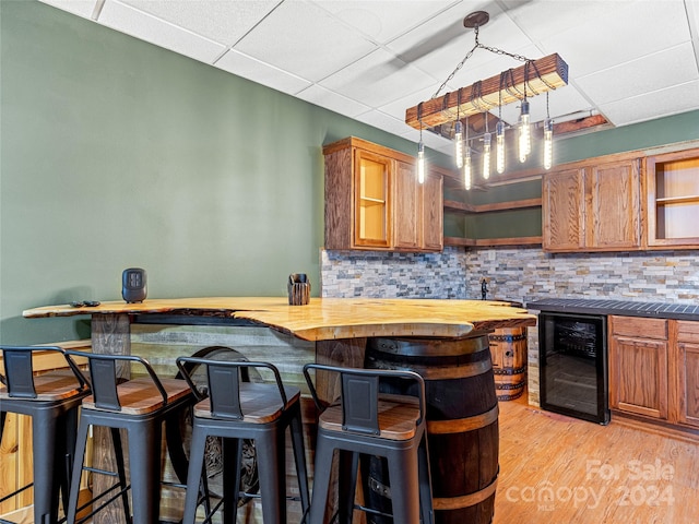 kitchen featuring wood counters, light hardwood / wood-style floors, wine cooler, and tasteful backsplash