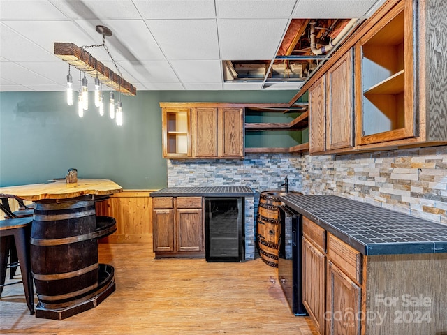 kitchen featuring decorative light fixtures, a kitchen breakfast bar, light wood-type flooring, and beverage cooler