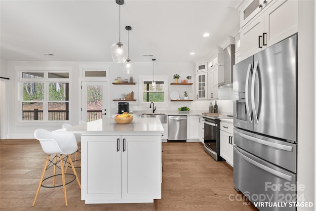 kitchen with white cabinets, a wealth of natural light, a center island, and appliances with stainless steel finishes