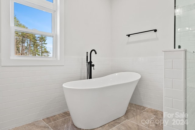 bathroom with tile walls and shower with separate bathtub