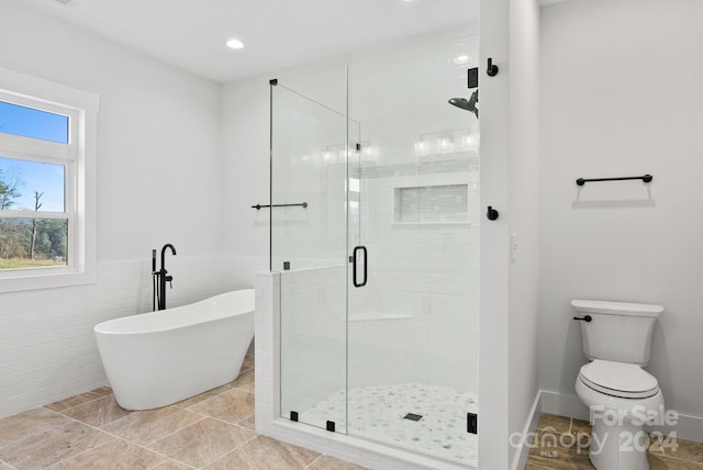 bathroom with tile patterned floors, toilet, tile walls, and independent shower and bath