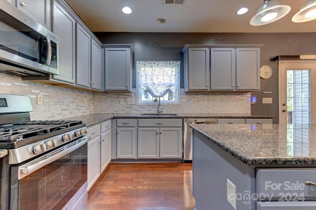 kitchen featuring decorative backsplash, dark hardwood / wood-style flooring, stainless steel appliances, sink, and pendant lighting