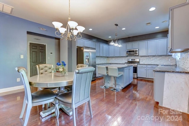 dining space with sink, a chandelier, and hardwood / wood-style flooring