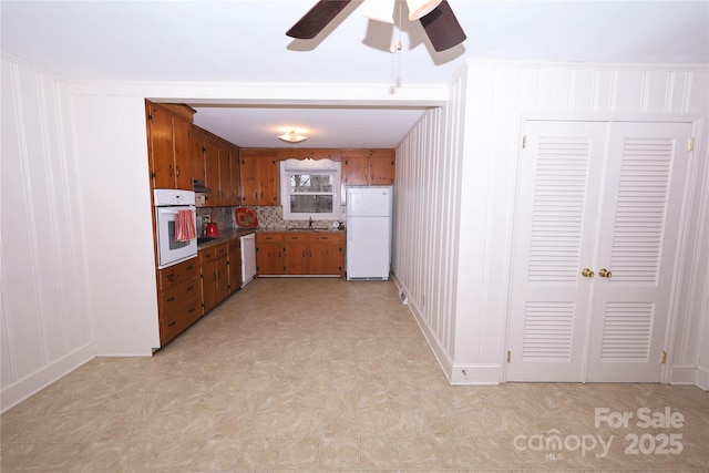 kitchen with tasteful backsplash, ceiling fan, sink, and white appliances