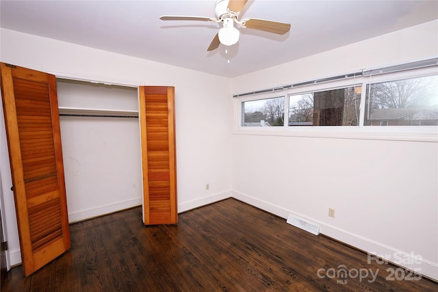 unfurnished bedroom with dark hardwood / wood-style flooring, a closet, and ceiling fan