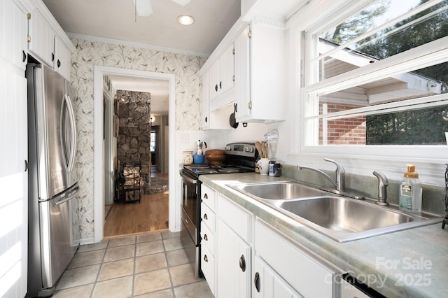 kitchen with white cabinets, appliances with stainless steel finishes, light tile patterned flooring, and sink