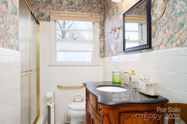 bathroom with tile walls, plenty of natural light, vanity, and toilet