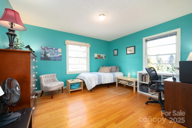 bedroom featuring a textured ceiling, multiple windows, and light hardwood / wood-style floors