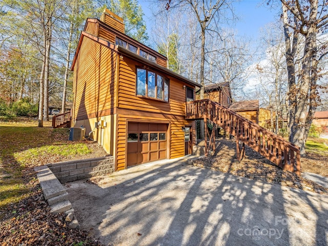 view of side of home with a garage and central air condition unit