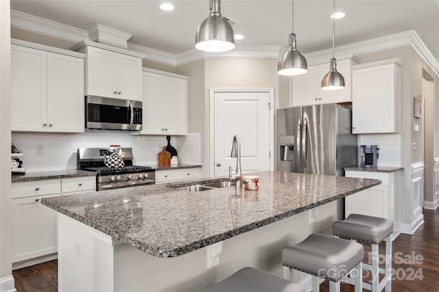 kitchen featuring appliances with stainless steel finishes, dark wood-type flooring, sink, white cabinetry, and hanging light fixtures