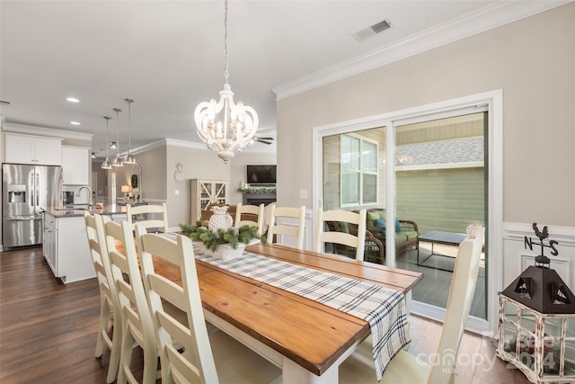 dining area featuring dark hardwood / wood-style floors, sink, crown molding, and an inviting chandelier