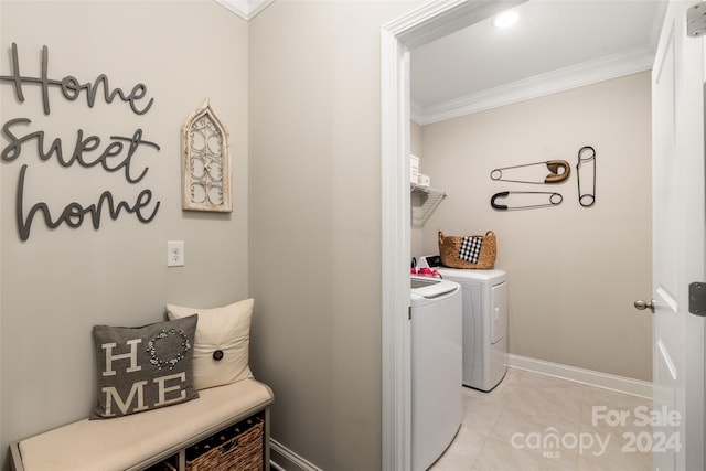 clothes washing area with washing machine and dryer, ornamental molding, and light tile patterned floors