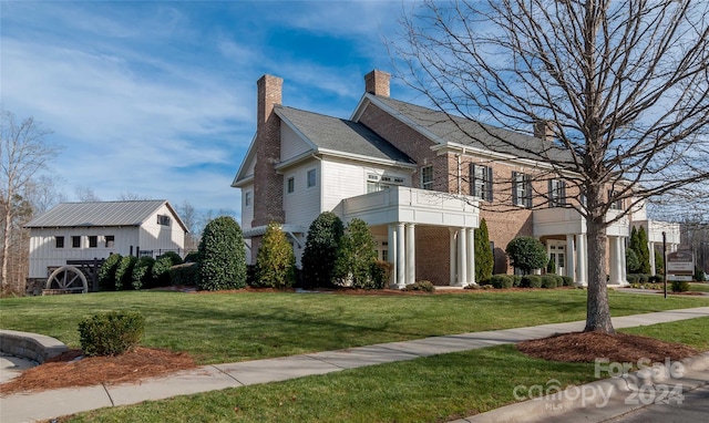 view of side of property featuring a yard and a balcony