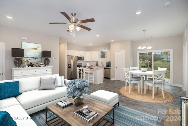 living room featuring dark hardwood / wood-style flooring, ceiling fan with notable chandelier, and sink