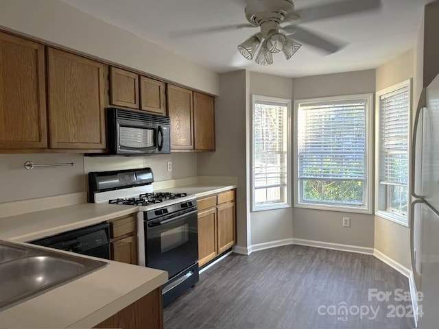 kitchen featuring black appliances, dark hardwood / wood-style floors, ceiling fan, and sink