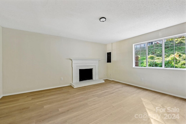 unfurnished living room with a fireplace, a textured ceiling, and light hardwood / wood-style flooring