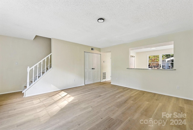 unfurnished room featuring light hardwood / wood-style floors and a textured ceiling