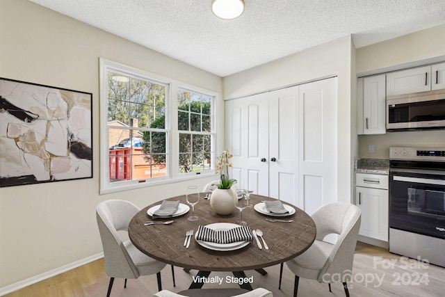 dining space featuring a textured ceiling and light hardwood / wood-style flooring