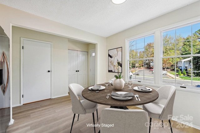 dining area with light hardwood / wood-style floors and a textured ceiling