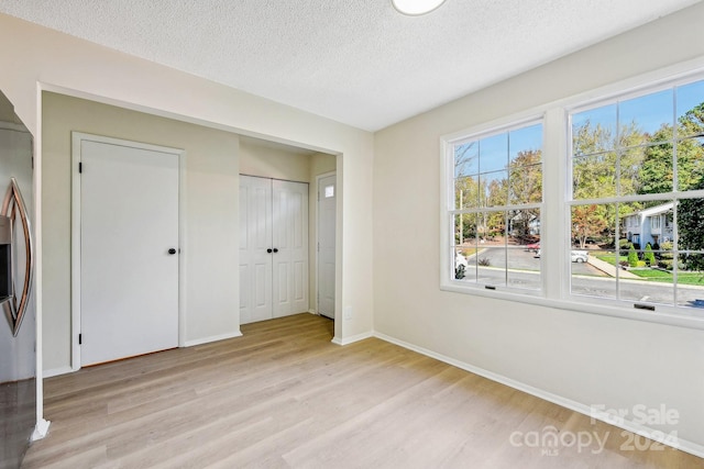 unfurnished bedroom with a textured ceiling and light wood-type flooring