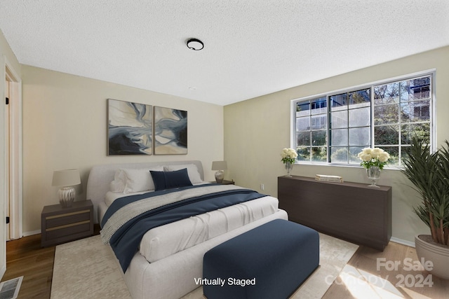 bedroom with light hardwood / wood-style floors and a textured ceiling