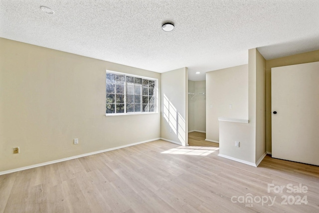 spare room with a textured ceiling and light wood-type flooring