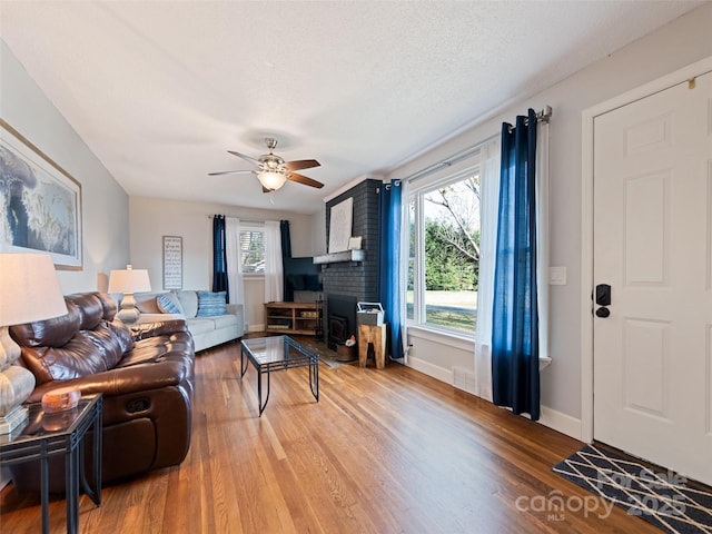 living room featuring ceiling fan, a healthy amount of sunlight, a textured ceiling, and light wood-type flooring