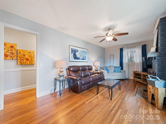 living room with ceiling fan, a fireplace, a textured ceiling, and hardwood / wood-style flooring